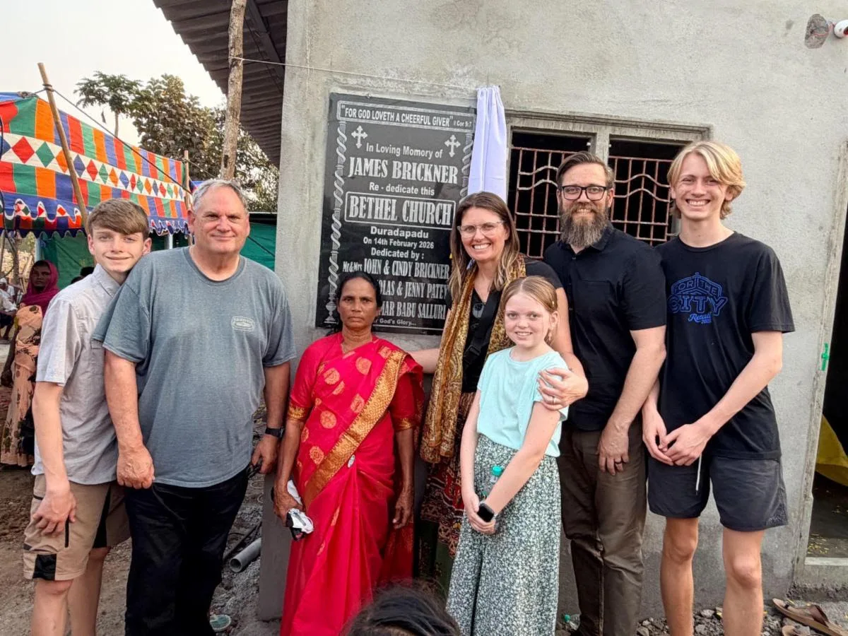 Nick and Jennifer Patey's family with church members at the Bethel Church dedication plaque in Duradapadu